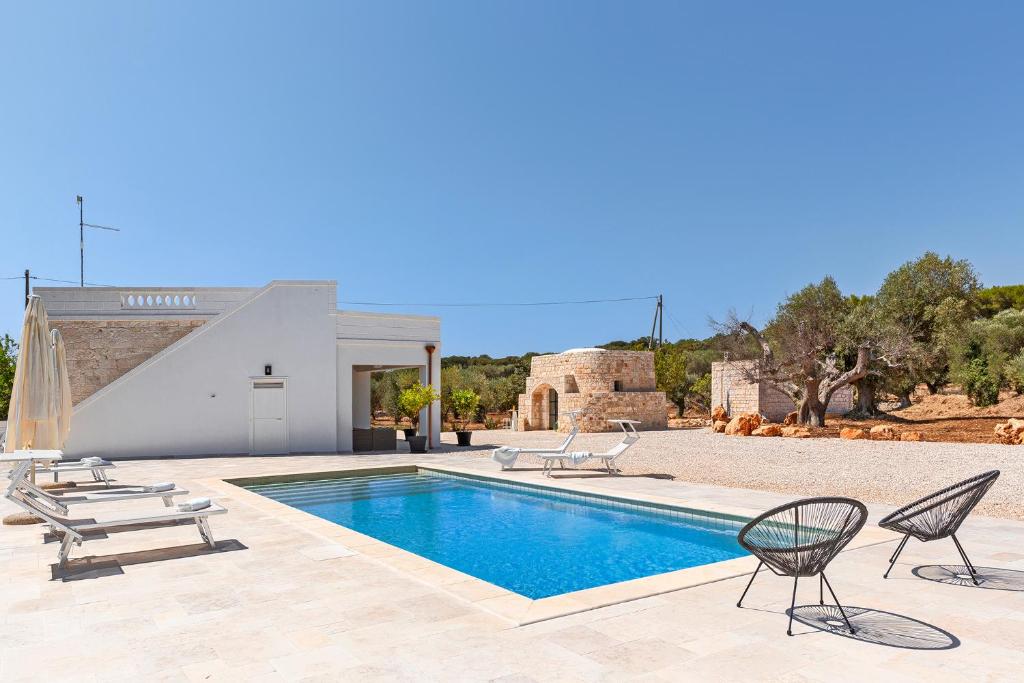 une villa avec une piscine et deux chaises dans l'établissement Vilaa Isa Beautiful Villa and trullo in Ostuni, à Ostuni