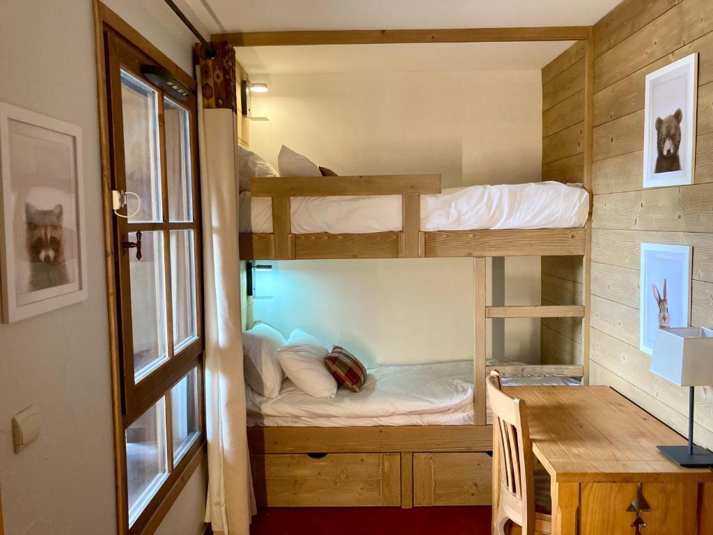 une chambre avec deux lits superposés et un bureau dans l'établissement Appartement ARC 1950 m, Ski au pied, piscine extérieure chauffée, remontées mécaniques à 100m, sauna et salle de sports, à Arc 1950