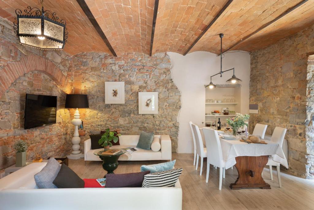 - un salon avec un mur en pierre, une table et des chaises dans l'établissement Villa Fracassini, à Pergine Valdarno