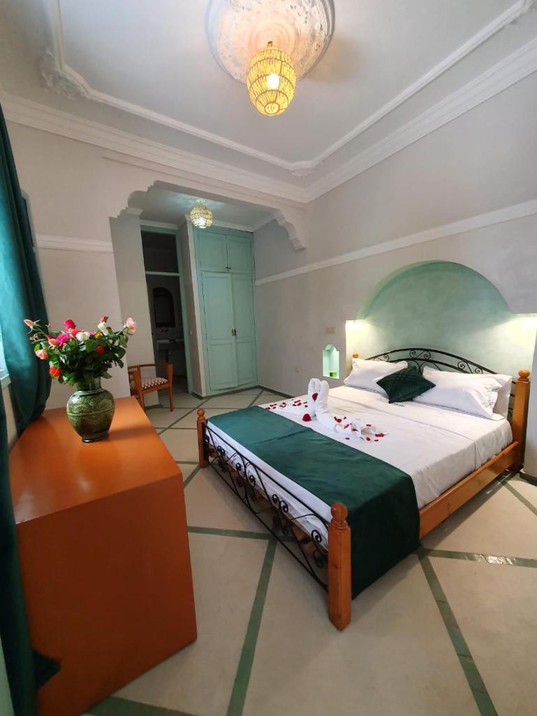 une chambre avec un lit et un vase de fleurs sur une table dans l'établissement Dar "JENNA-ROSE", à Marrakech