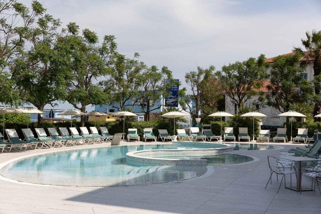 une grande piscine avec chaises et parasols dans l'établissement Blu Suite Resort, à Bellaria-Igea Marina