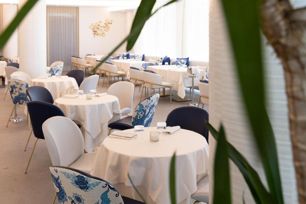 une chambre avec des tables et des chaises, des tables blanches et des chaises bleues dans l'établissement Blu Suite Resort, à Bellaria-Igea Marina