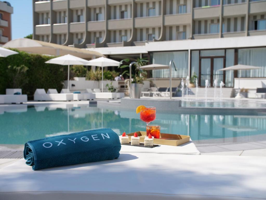 - une table au bord de la piscine avec une boisson et un verre dans l'établissement Oxygen Lifestyle Hotel, à Rimini