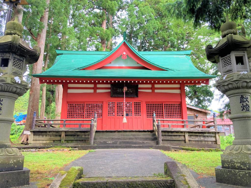 un bâtiment rouge avec un toit vert dans un parc dans l'établissement Tabataya, à Myōkō