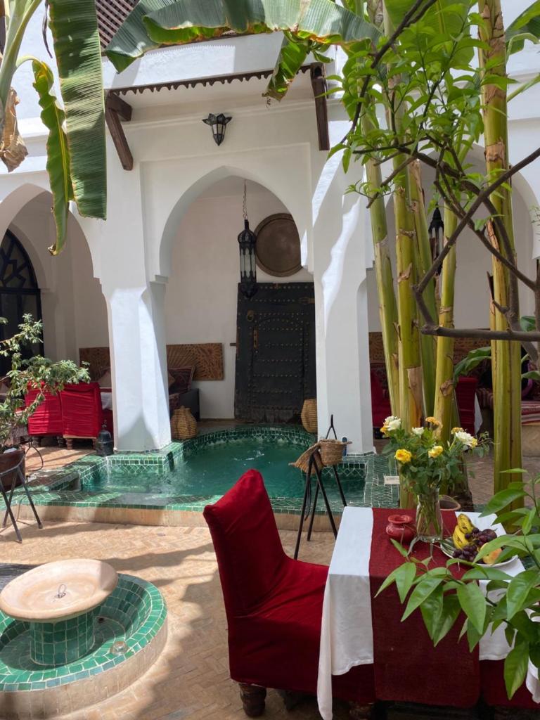un salon avec une chaise rouge et une table dans l'établissement Dar Soukaina, à Marrakech