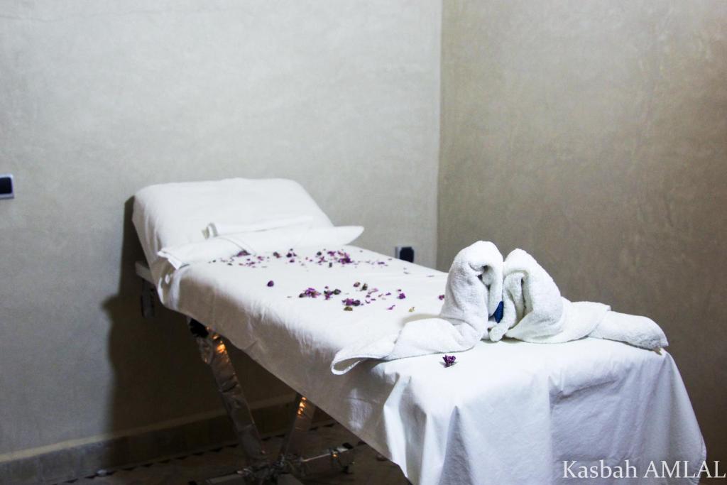 un lit d'hôpital avec des serviettes blanches et des fleurs dessus dans l'établissement kasbah amlal, à Boumalne