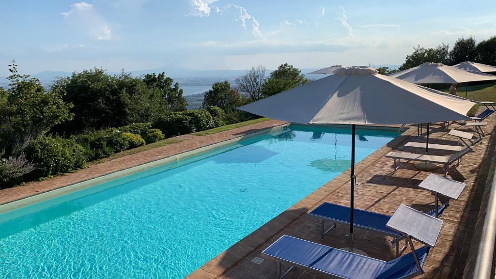 une piscine avec des chaises et un parasol dans l'établissement Villa Gosparini, à Lisciano Niccone