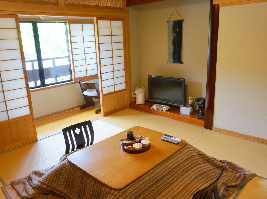 un salon avec une table et une télévision dans l'établissement Ryokan Yamashiroya, à Yufu