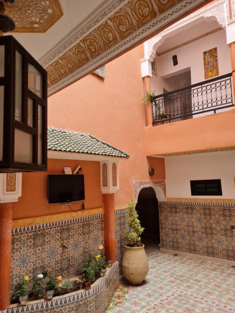 une cour d'un bâtiment avec une télévision murale dans l'établissement Riad Kanata, à Marrakech