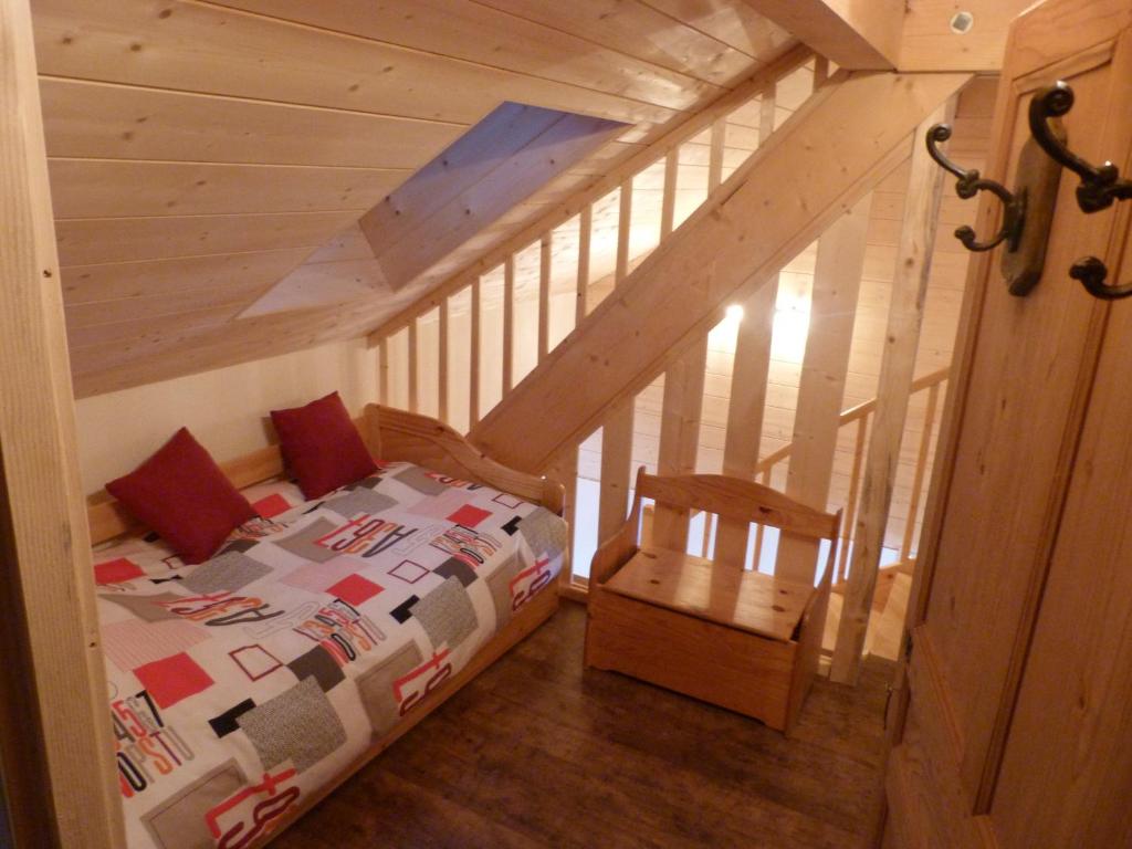 une chambre avec un lit et une chaise dans un grenier dans l'établissement Gite du Brin d'Herbe, à Pontarlier