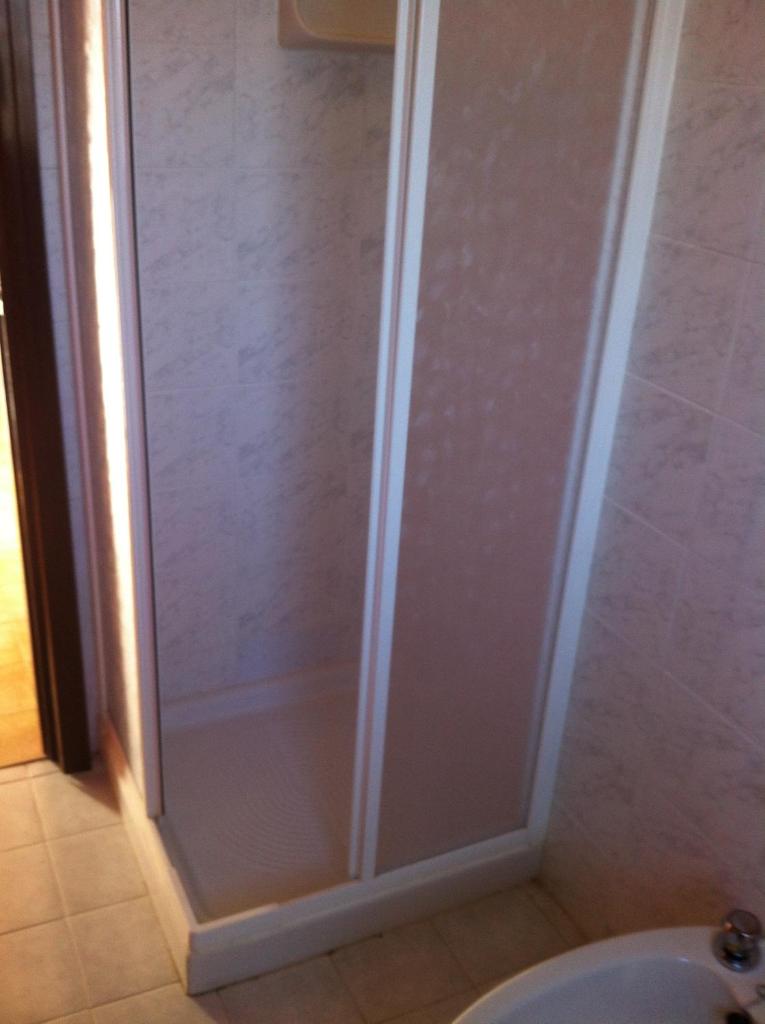 une douche avec une porte vitrée dans une salle de bain dans l'établissement Amanda Appartamenti Trilocali, à Lido Adriano