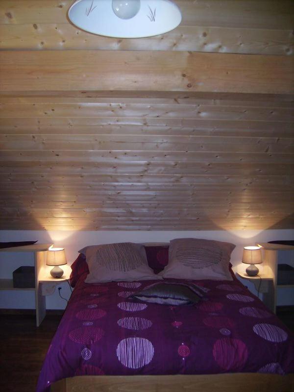 une chambre avec un lit violet avec deux lampes dans l'établissement Gite du Brin d'Herbe, à Pontarlier