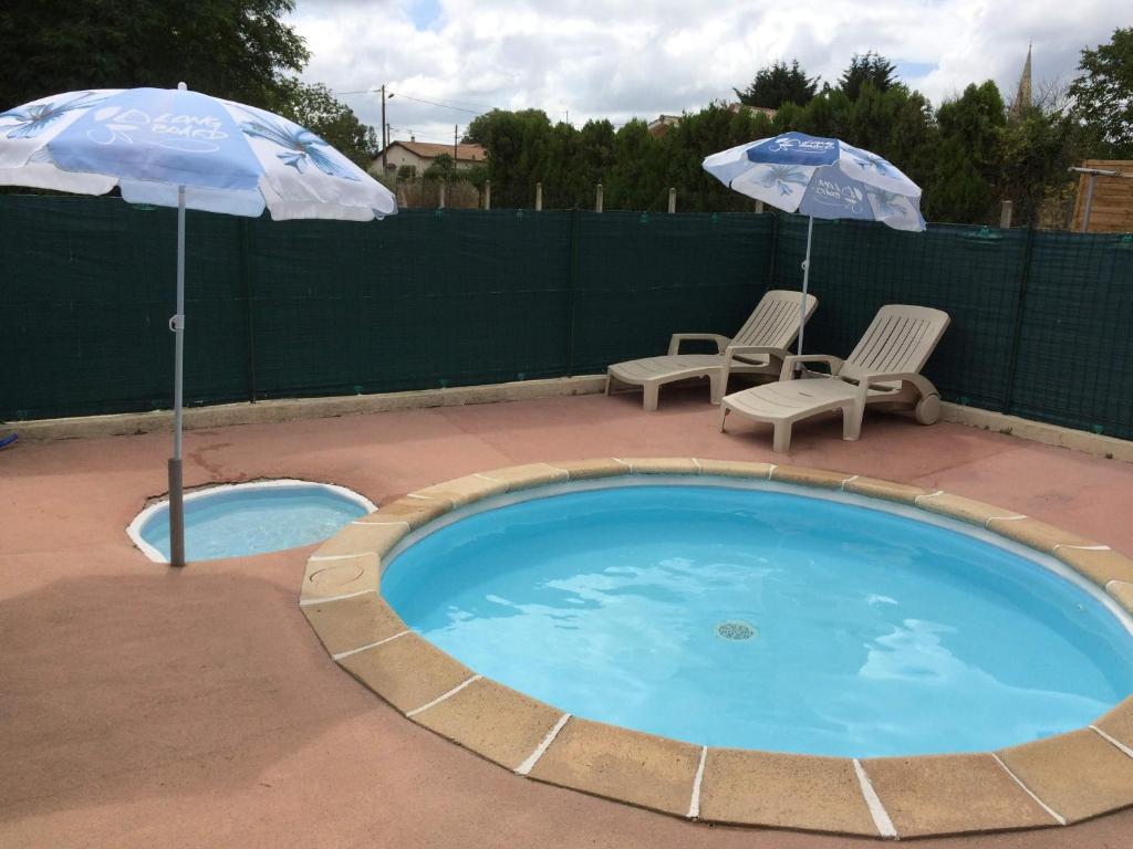 - deux parasols et des chaises à côté de la piscine dans l'établissement GITE DES PHARES - Day Cruise en bateau privé, pêche en mer, et visite guidée des Chateaux du Médoc, à Lesparre-Médoc