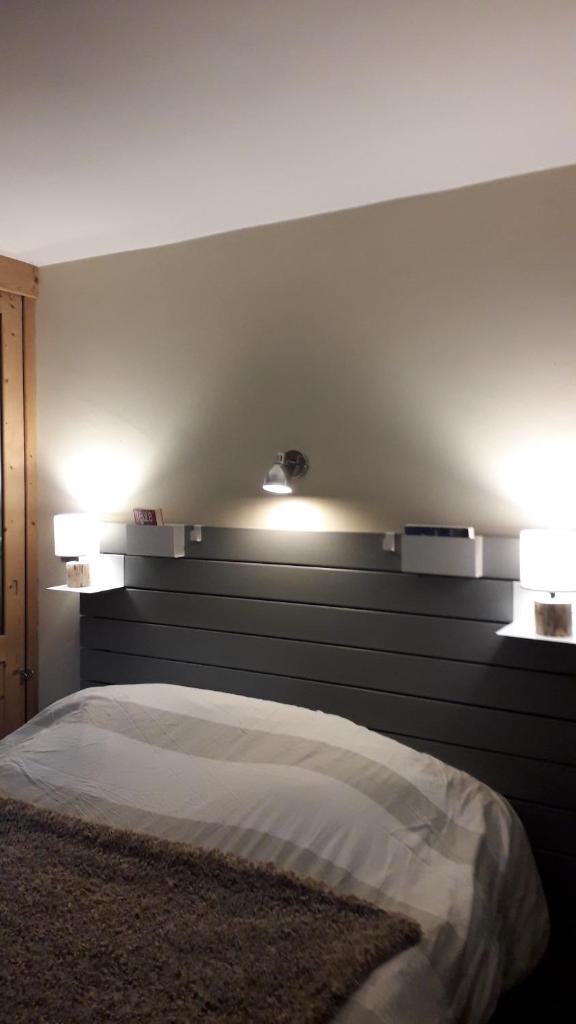 - une chambre avec un lit et deux lumières sur le mur dans l'établissement A Cordon entre Bois et Nature, à Cordon
