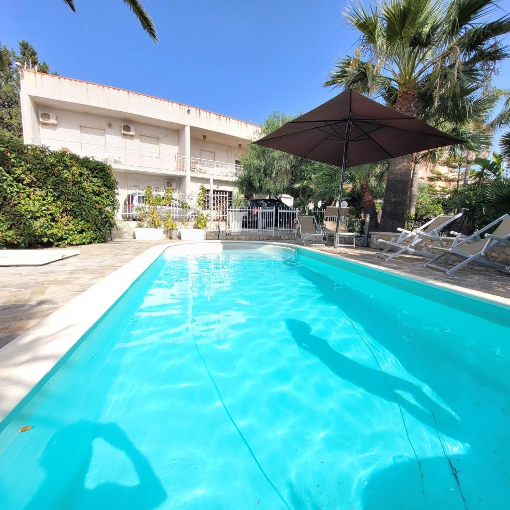 - une piscine avec un parasol dans l'établissement Villa Virginia, à Pellaro