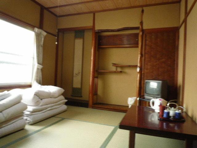 Cette chambre comprend des lits superposés et une table avec une télévision. dans l'établissement Daiya Ryokan, à Kyoto
