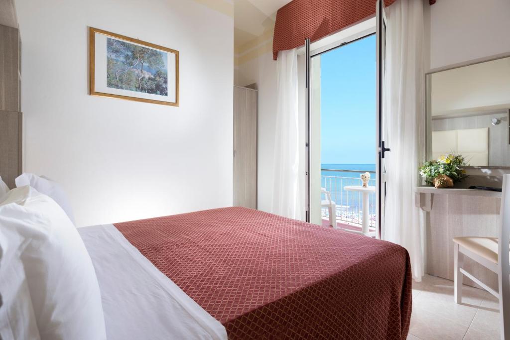 une chambre avec un lit et une vue sur l'océan dans l'établissement Hotel Vela d'Oro, à Rimini