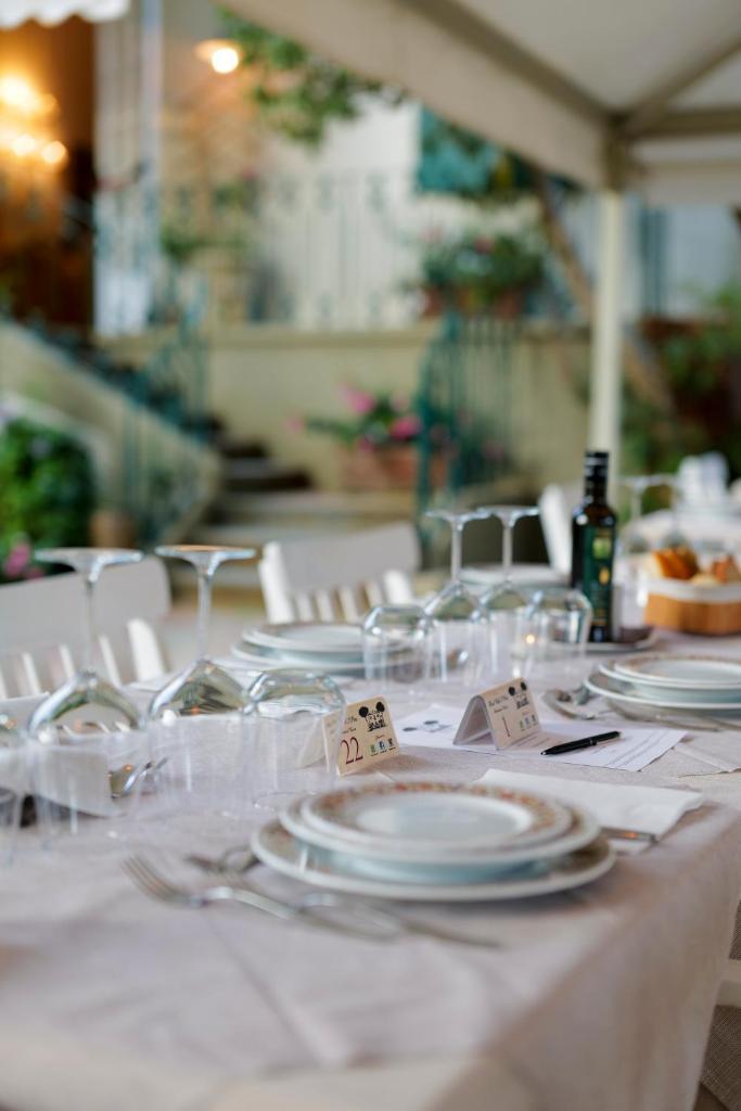 une table avec des assiettes et des verres blancs dans l'établissement Hotel Club i Pini - Residenza d'Epoca in Versilia, à Lido di Camaiore