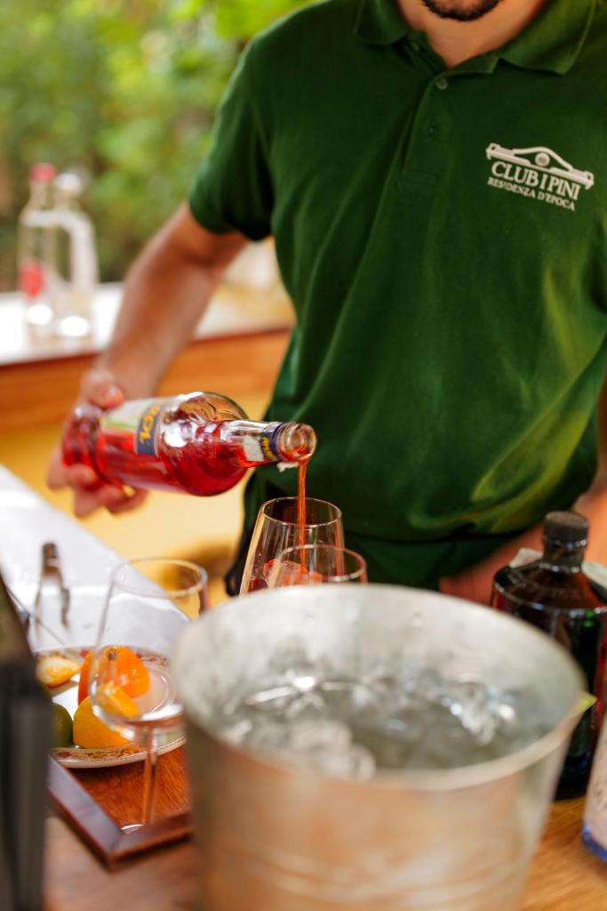 un homme versant une boisson dans un verre sur un comptoir dans l'établissement Hotel Club i Pini - Residenza d'Epoca in Versilia, à Lido di Camaiore