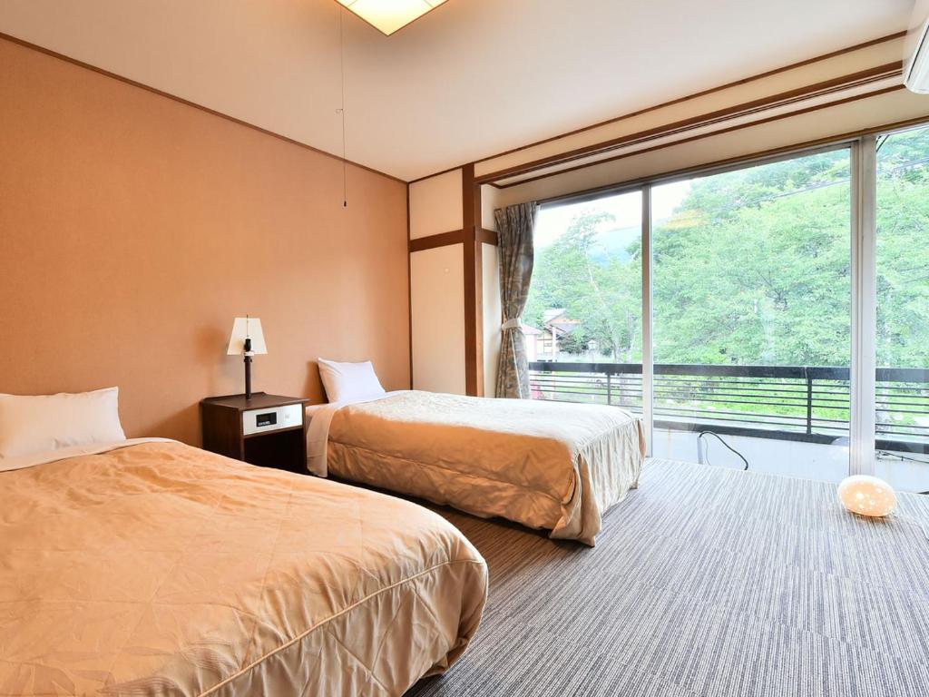 une chambre d'hôtel avec deux lits et une grande fenêtre dans l'établissement Alpine Route Hotel, à Omachi 33 autres photos