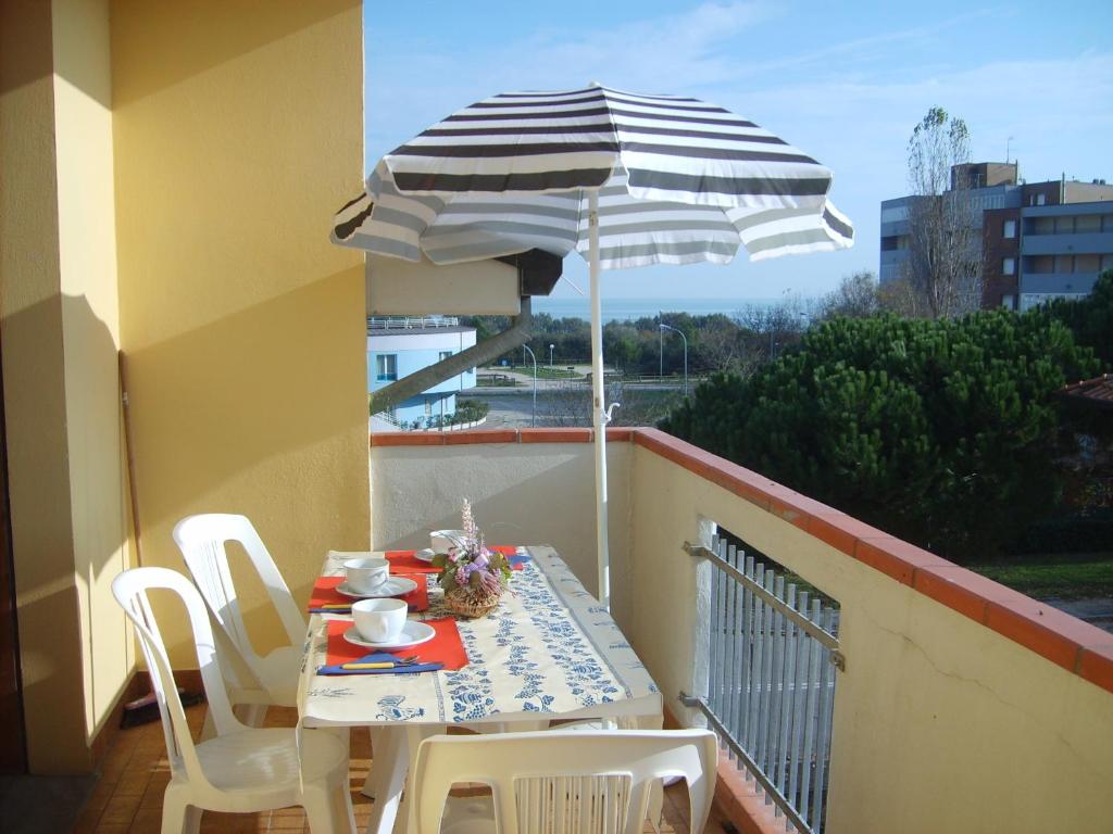 une table et des chaises avec un parasol sur un balcon dans l'établissement Amanda Appartamenti Trilocali, à Lido Adriano