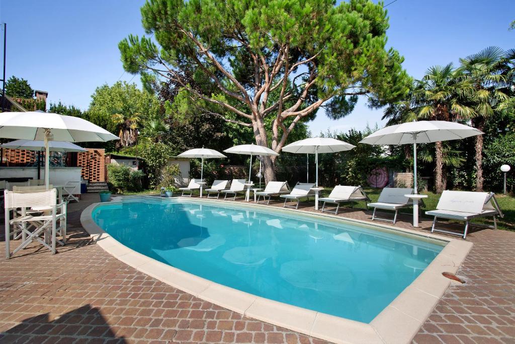 une piscine avec chaises et parasols dans l'établissement Villa La Palmetta, à Peschiera Borromeo