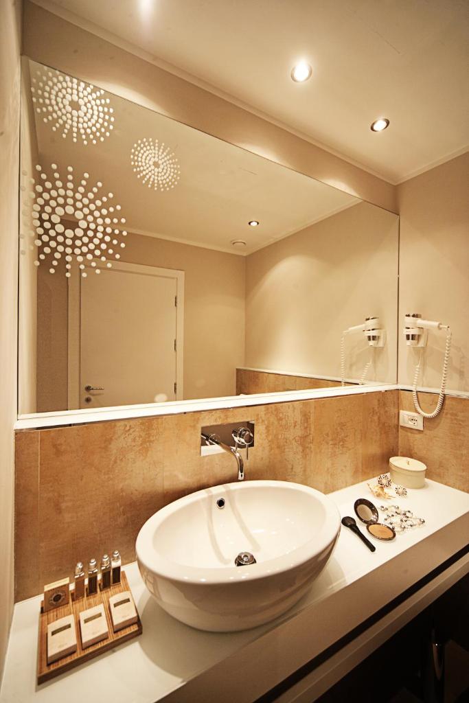 une salle de bain avec un lavabo et un grand miroir dans l'établissement Oxygen Lifestyle Hotel, à Rimini