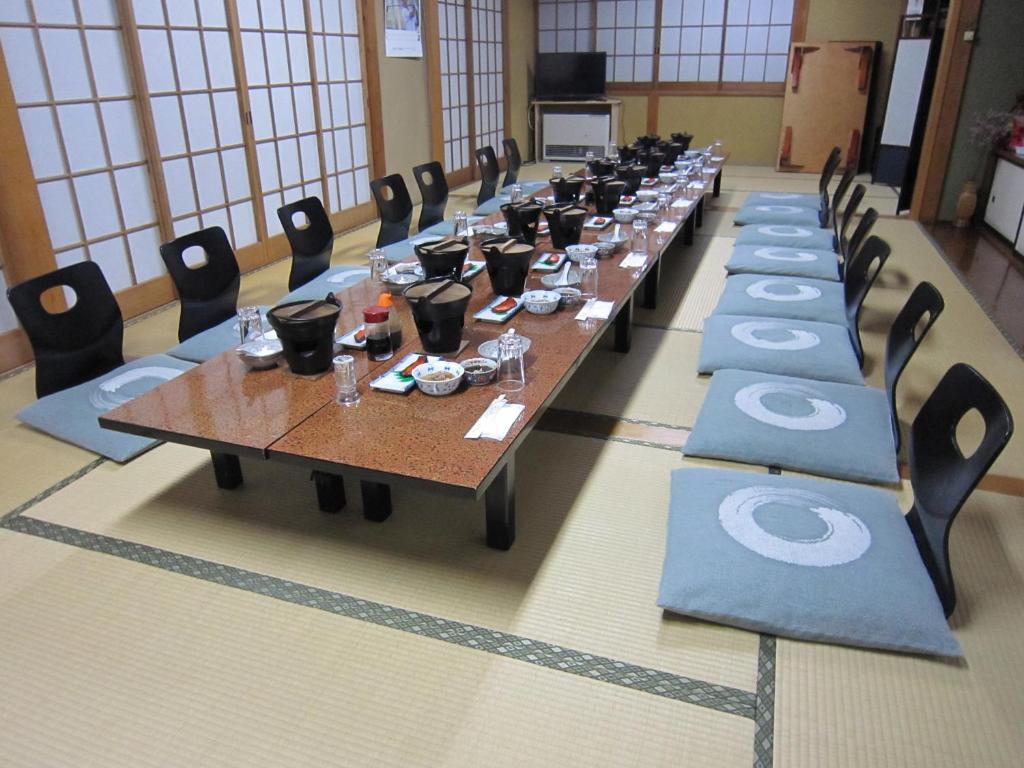 une longue rangée de tables dans une pièce avec des chaises dans l'établissement Minshuku Kobayashi, à Narusawa