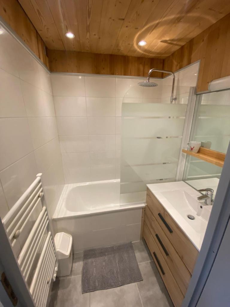 une salle de bain avec une baignoire blanche et un lavabo dans l'établissement Chaleureux appartement rénové ambiance chalet, à Praz-sur-Arly
