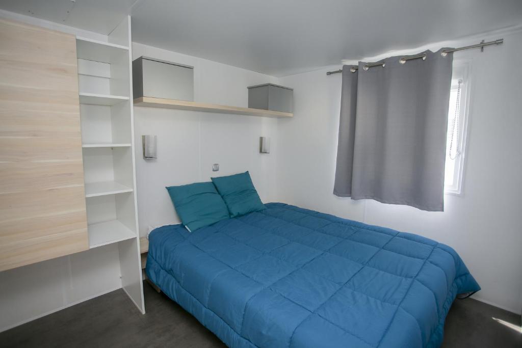 Cette petite chambre comprend un lit bleu et des étagères. dans l'établissement Camping du Lac, à Foix