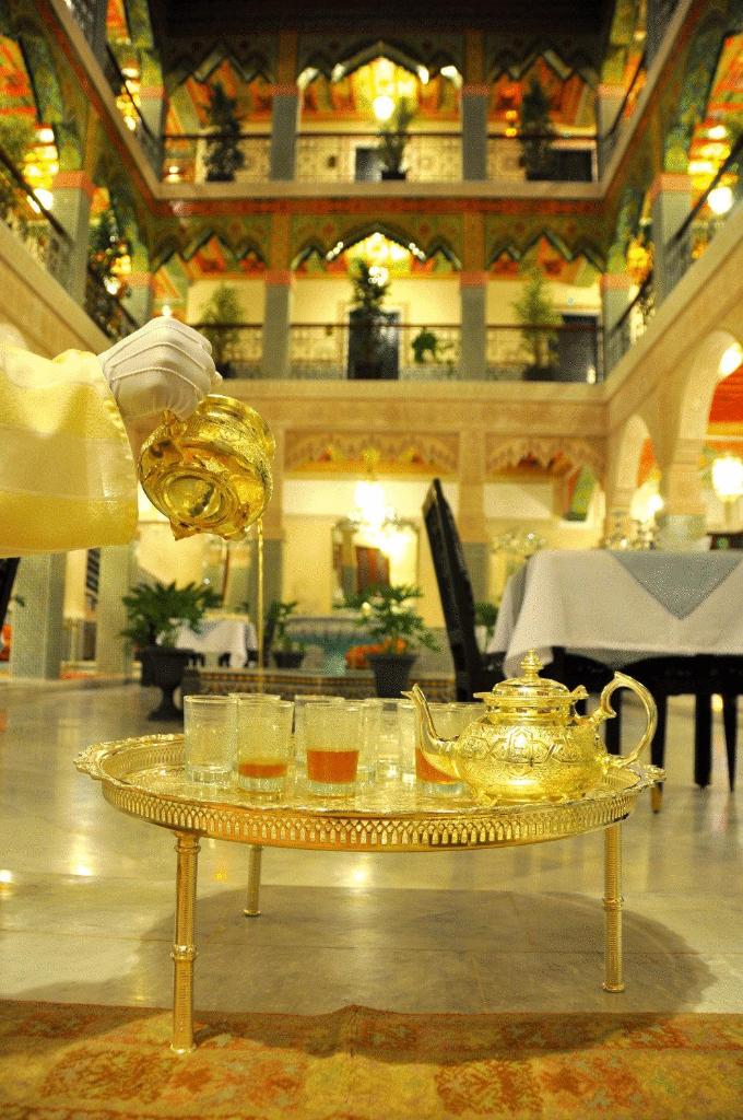 - un plateau de friandises en or avec des verres et un service à thé sur une table dans l'établissement Palais Riad Reda & Spa, à Fès