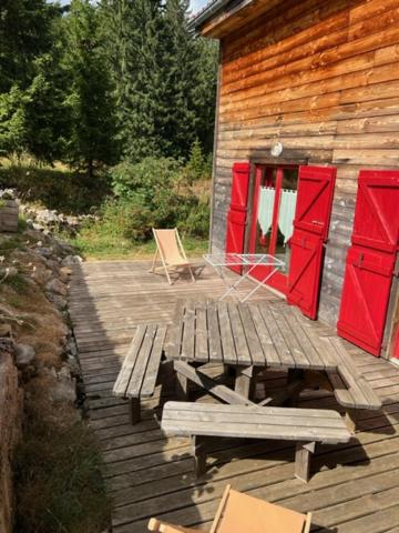 une terrasse en bois avec des portes rouges et un banc sur une cabine dans l'établissement Chalet 8-10 personnes sur la station des Rousses, à Lamoura