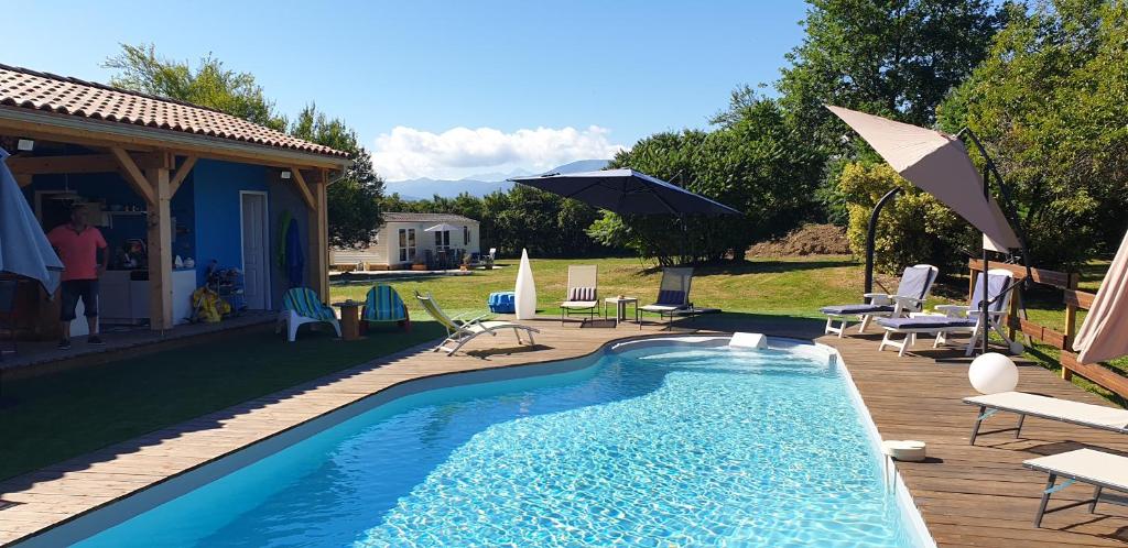 - une piscine avec des chaises et des parasols à côté d'une maison dans l'établissement Les chalets Salinéens, à Salies-du-Salat