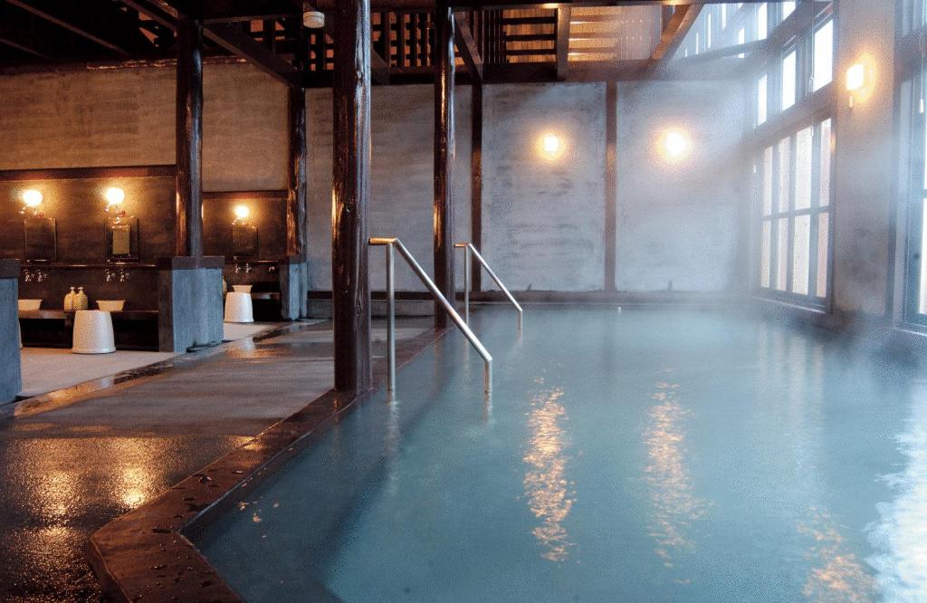 - une piscine d'eau bleue dans une chambre avec fenêtres dans l'établissement Hirayunomori, à Takayama