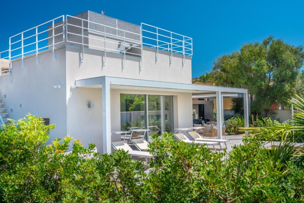 une maison blanche avec un balcon et des chaises dans l'établissement Villa Kòsmos - Piscina e Giardino - Villasimius, à Simius