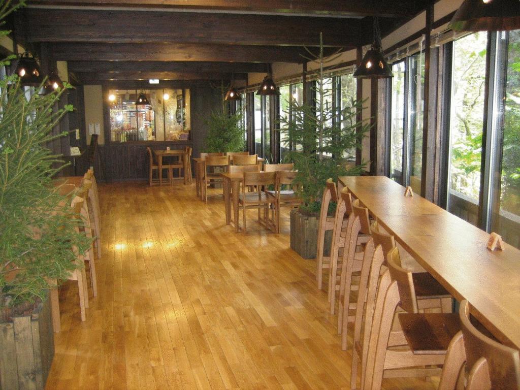 un restaurant avec des tables et des chaises en bois et des fenêtres dans l'établissement Hirayunomori, à Takayama