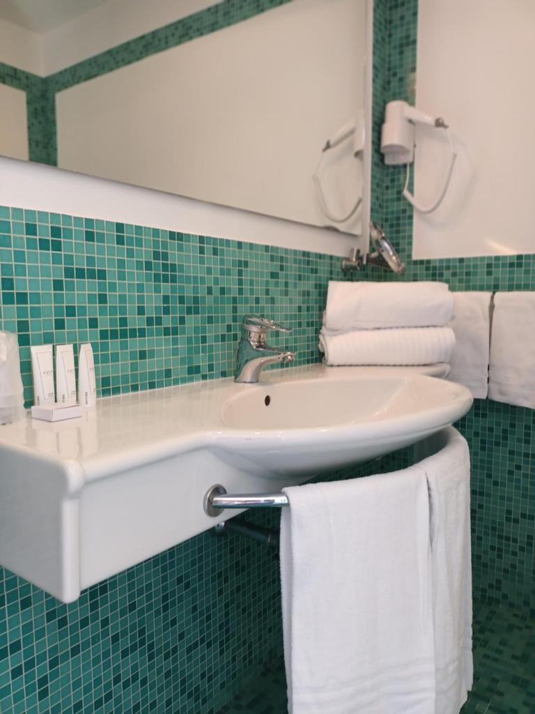 une salle de bain avec un lavabo, un miroir et des serviettes dans l'établissement Residence al Palace, à Vasto 45 autres photos