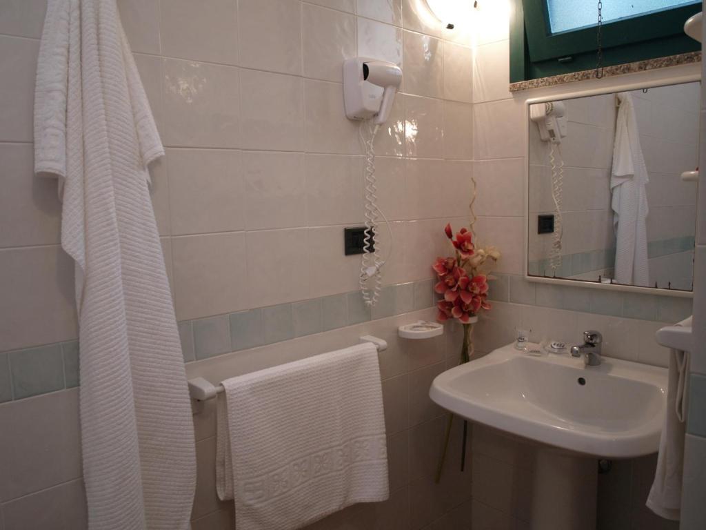 une salle de bain blanche avec un lavabo et un miroir dans l'établissement Club Esse Cala Bitta, à Baja Sardinia