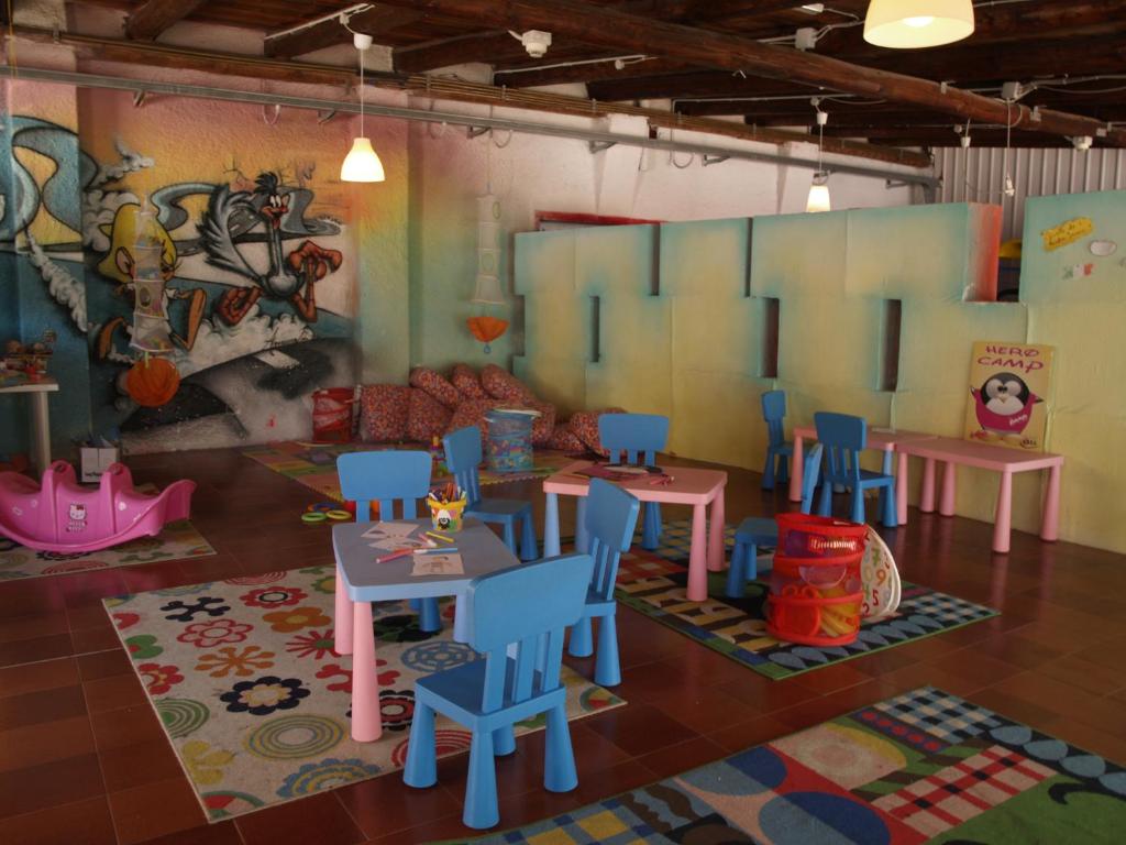 - une salle de jeux avec des tables, des chaises et un mur dans l'établissement Club Esse Cala Bitta, à Baja Sardinia