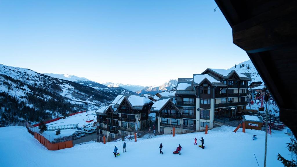 - un groupe de personnes skier dans la neige devant un lodge dans l'établissement Hôtel Club "Les Carrettes", à Valmeinier