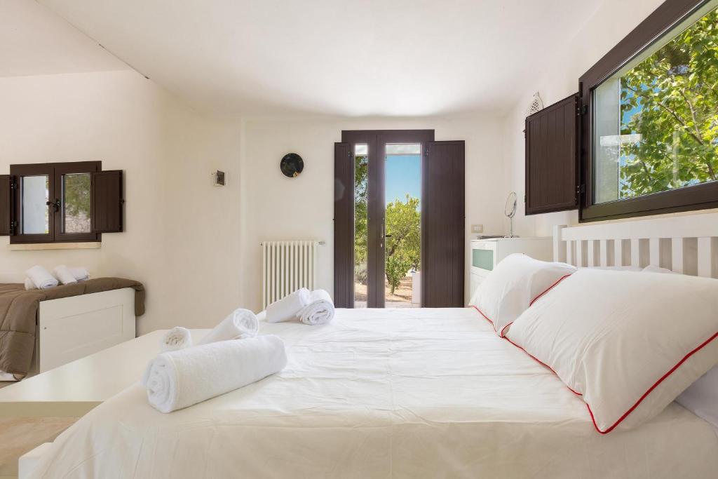 un grand lit blanc dans une chambre avec une fenêtre dans l'établissement Villa Sessana by Perle di Puglia, à Ceglie Messapica