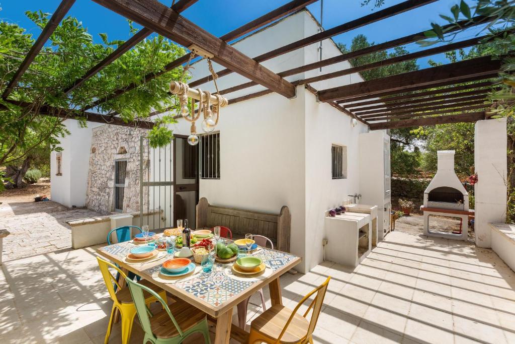 un patio avec une table, des chaises et une cheminée dans l'établissement Villa Sessana by Perle di Puglia, à Ceglie Messapica