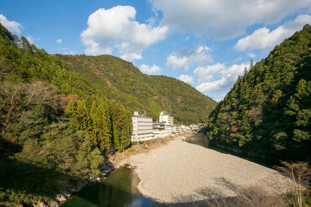Vue aride d'une rivière avec des bâtiments sur une montagne dans l'établissement Sansuikan Kawayu Midoriya, à Hongu