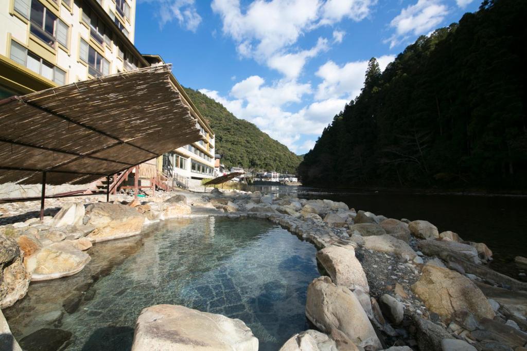 un grand bassin d'eau à côté d'une rivière dans l'établissement Sansuikan Kawayu Midoriya, à Hongu