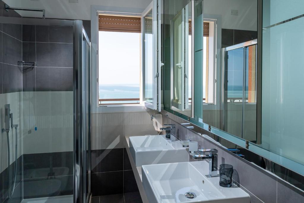 une salle de bain avec deux lavabos et un miroir dans l'établissement Hotel Sheila, à Lido di Jesolo