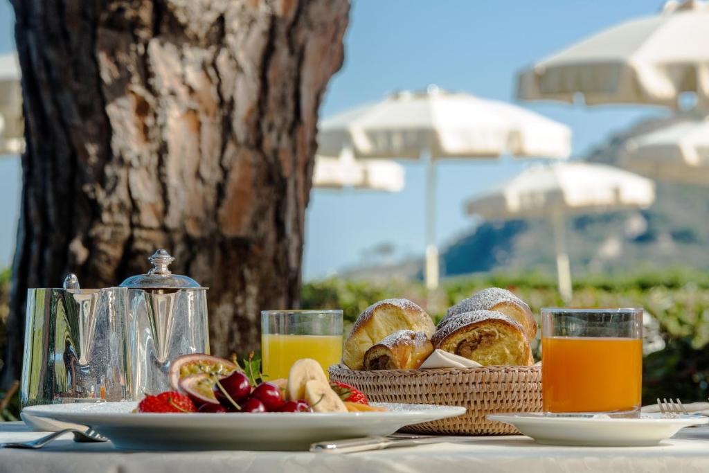 - une table avec du pain, du jus de fruits et une corbeille de fruits dans l'établissement Hotel Biodola, à Portoferraio