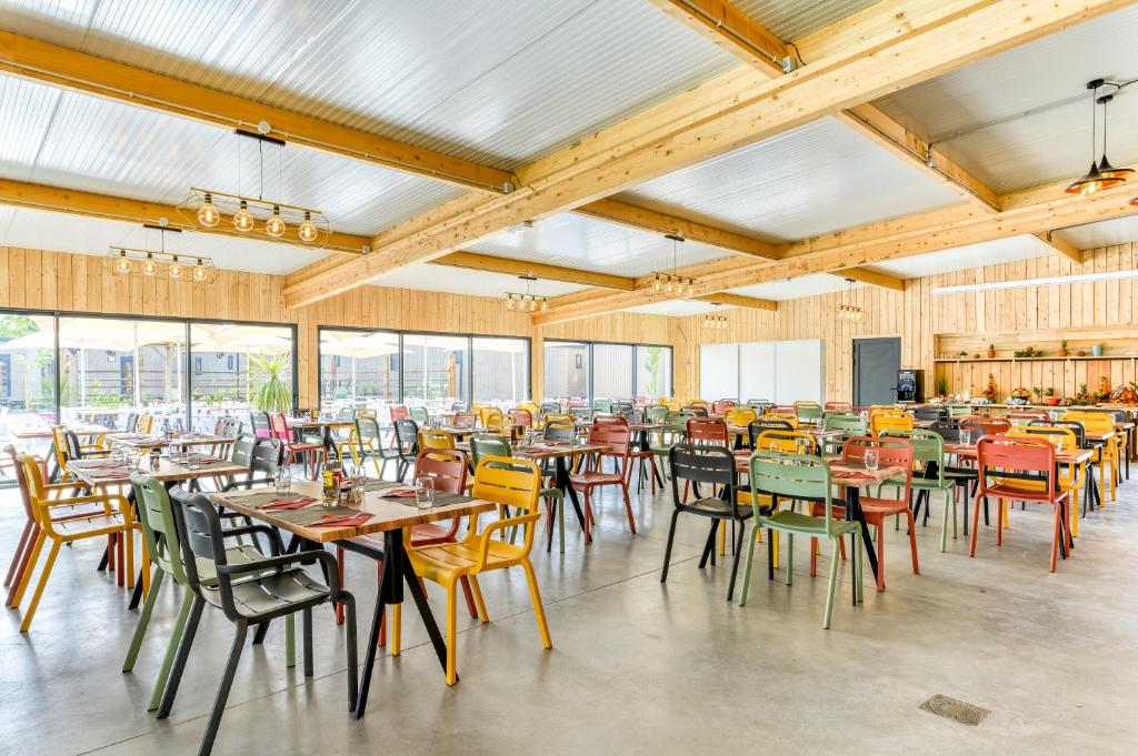 une grande salle à manger avec tables et chaises dans l'établissement Camping maeva Escapades Les Cottages de Perpignan, à Perpignan