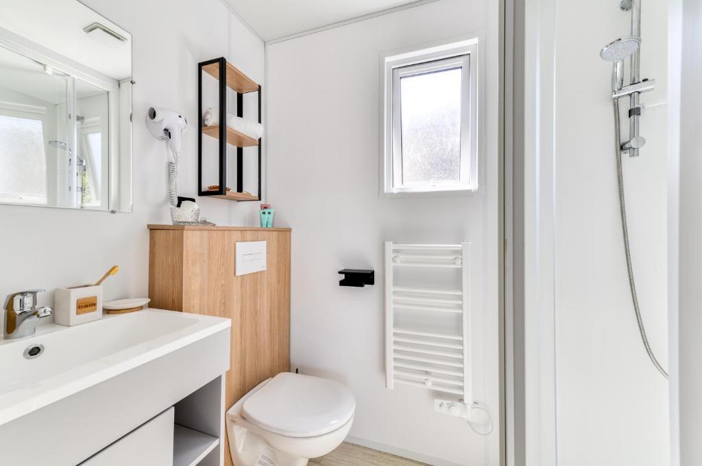 une salle de bain blanche avec des toilettes et un lavabo dans l'établissement Camping maeva Escapades Les Cottages de Perpignan, à Perpignan