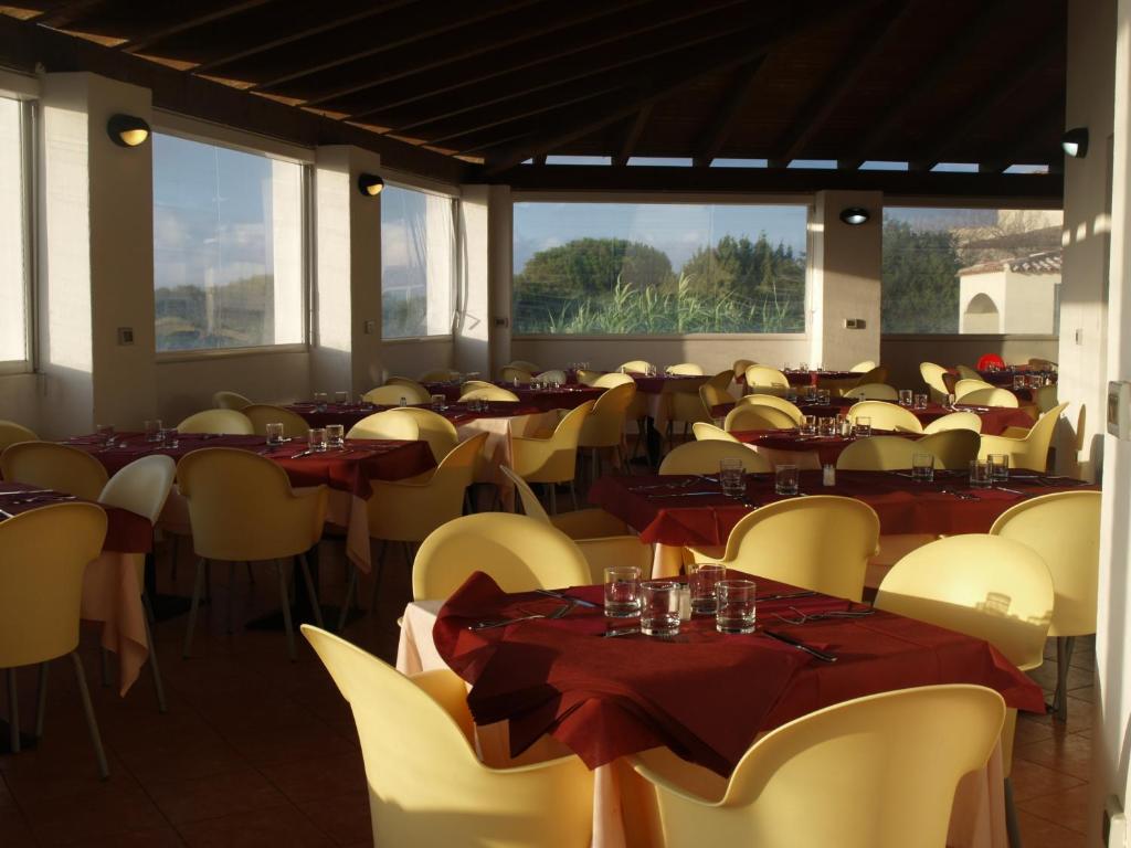 une salle à manger avec tables, chaises et fenêtres dans l'établissement Club Esse Gallura, à Aglientu