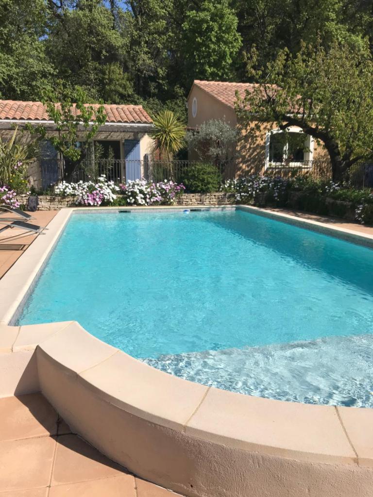 une piscine avec de l'eau bleue dans une cour dans l'établissement Les Hauts d'Eyragues gîte Aigue Marine Meublé classé 4 étoiles, à Eyragues